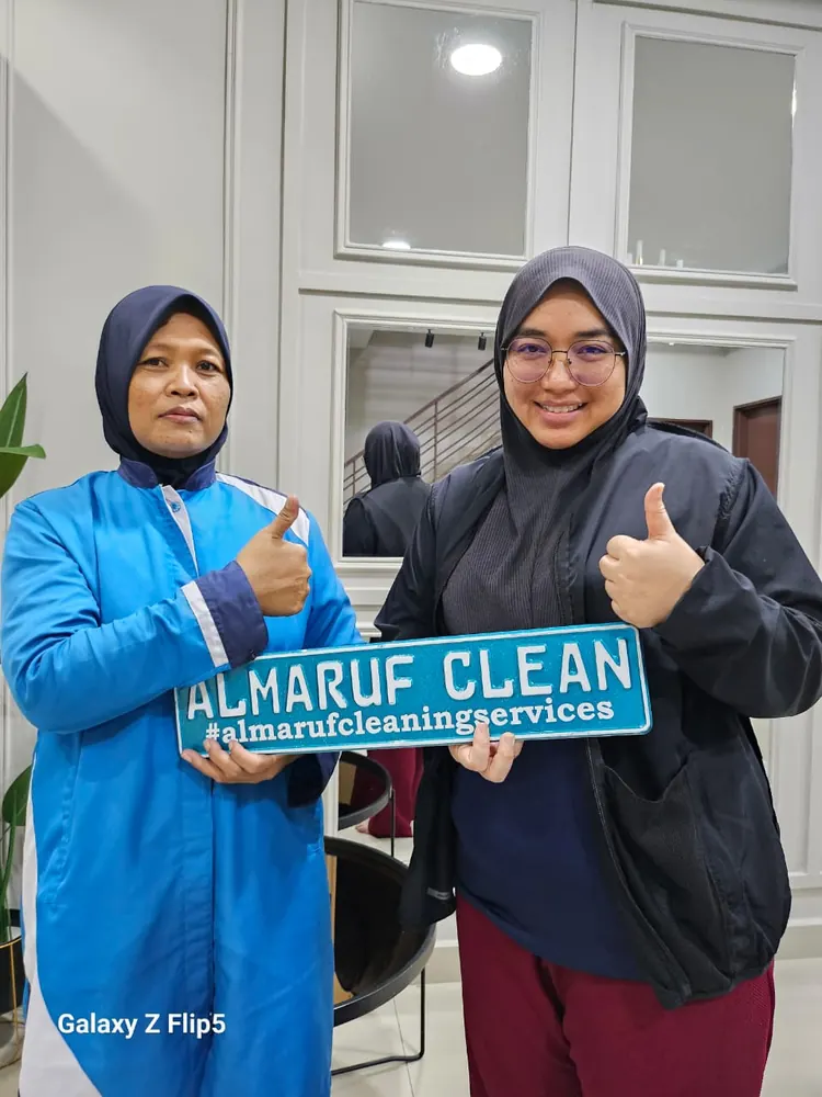 Almaruf Clean cleaner holding the Almaruf Clean sign with a customer after the job