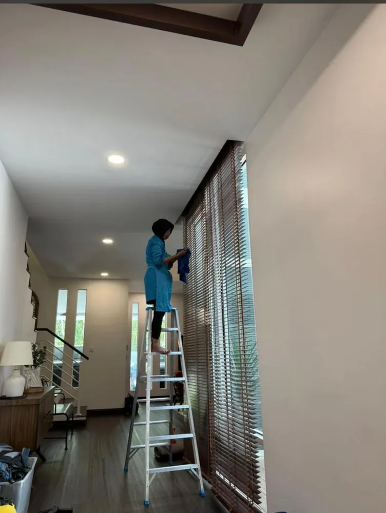 Dusting tall blinds in a hallway