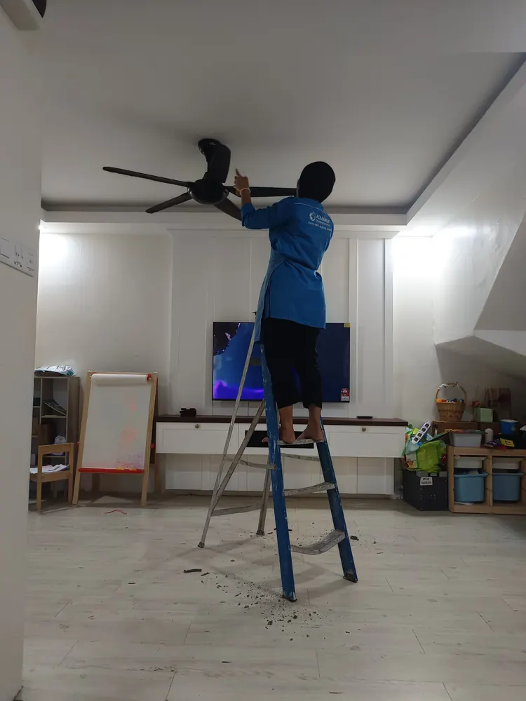 Wiping a ceiling fan from the ladder